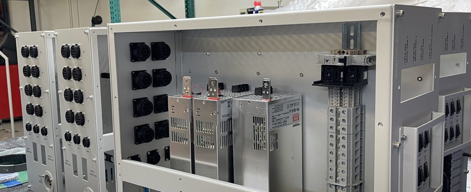 Open enclosure undergoing inspection, showing connector panel and power supplies